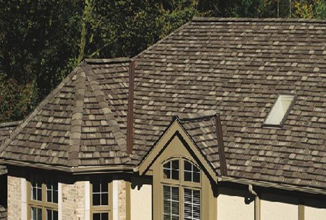 Installer nailing asphalt shingles during a roof installation
