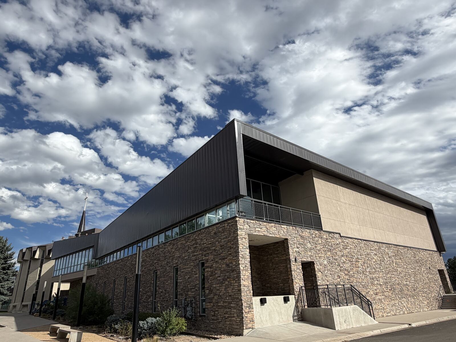 Church building addition with dark standing seam metal panels and stone walls