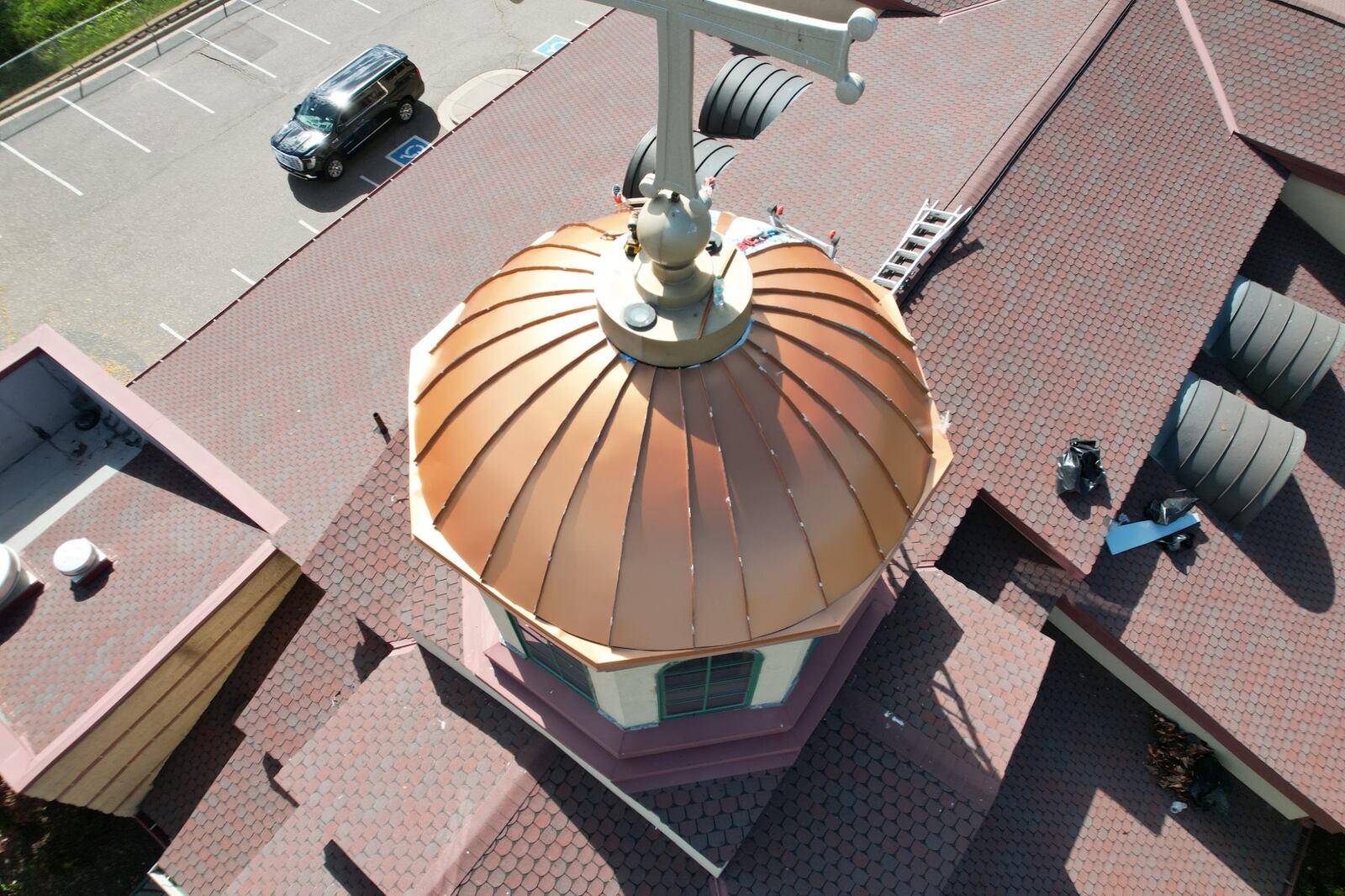 New copper standing seam dome on a church cupola, surrounded by a shingle roof