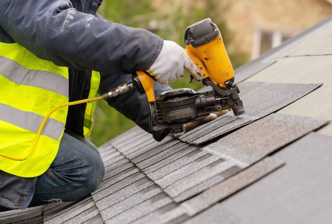 Roofer laying new shingles during a residential roof replacement